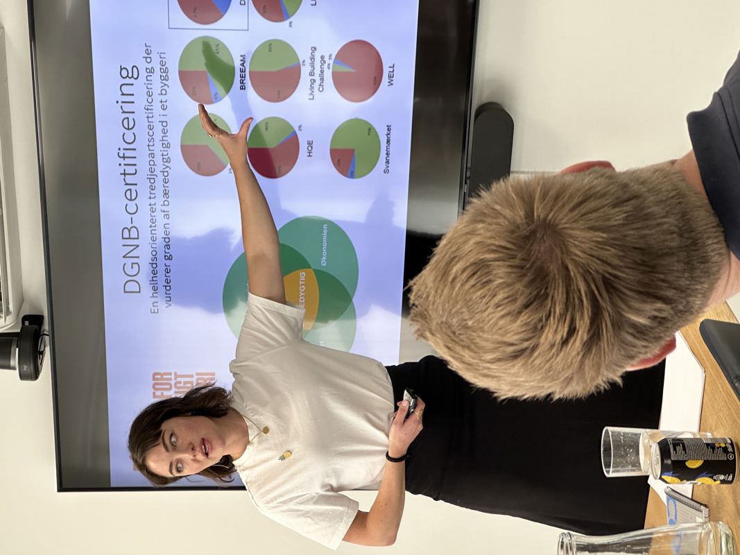 Kvinder peger på skærmen, mens hun vender hovedet mod medarbejderne og fortæller